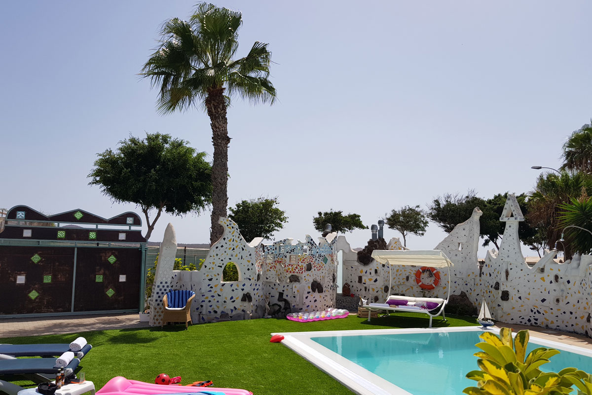 Pool im Freien mit buntem Zaun und Palme in Playa de Las Américas, Teneriffa.