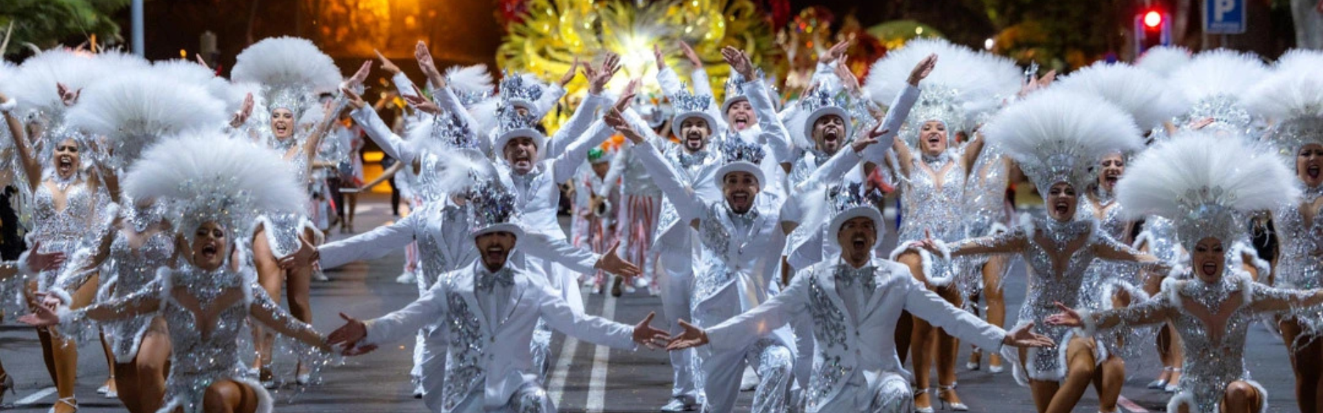 Tanzgruppe in weißen Kostümen tanzt und jubelt während des Karnevals in Santa Cruz de Tenerife.