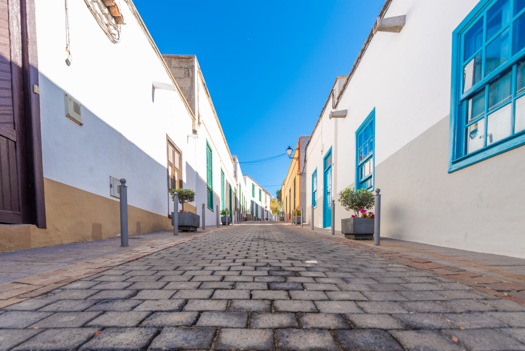 Kopfsteinpflasterstraße zwischen weißen Häusern mit blauen Fenstern auf Teneriffa.
