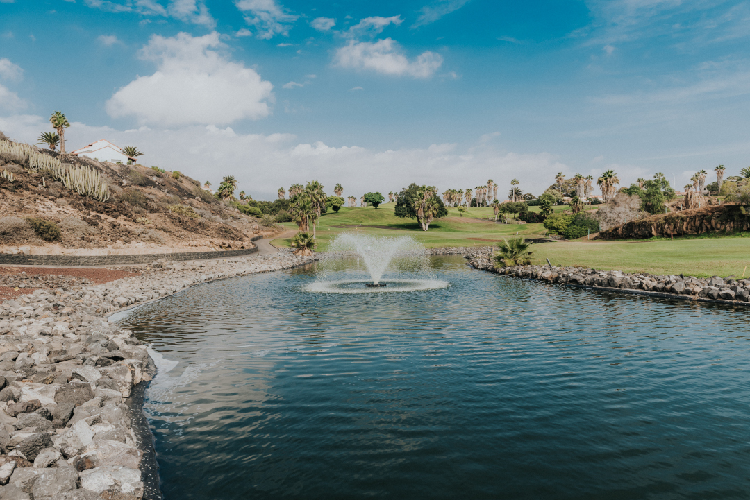 Brunnen in einem Teich, umgeben von Palmen, auf einem Golfplatz auf Teneriffa.