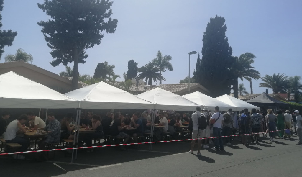 Menschen, die unter Zelten bei einer Outdoor-Veranstaltung auf Teneriffa zu Mittag essen.