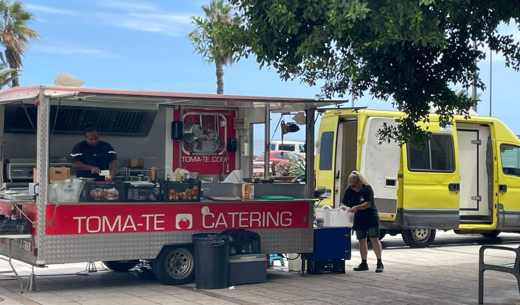 TOMA-TE Catering-Foodtruck auf Teneriffa mit Mitarbeitern, die Speisen zubereiten.
