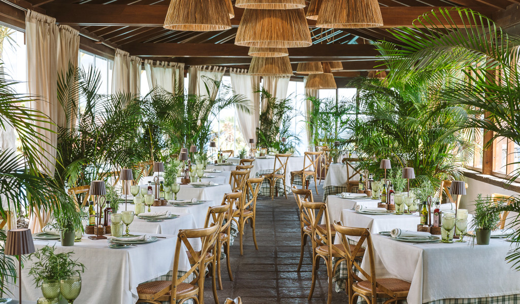 Restaurant auf Teneriffa mit mit Pflanzen dekorierten Tischen und reichlich natürlichem Licht.