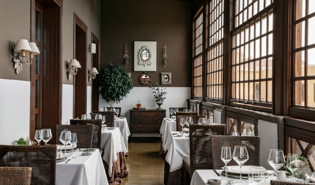 Speisesaal mit Weidentischen und Stühlen vor den Fenstern im Restaurant auf Teneriffa.