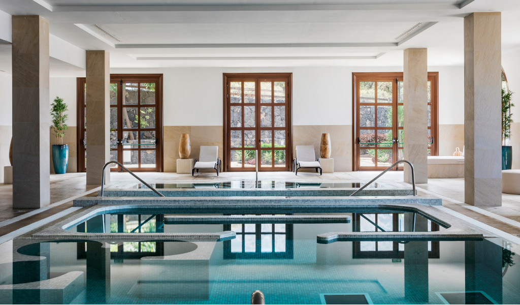 Hallenbad mit Sonnenliege und bodentiefen Fenstern in einem Spa auf Teneriffa.