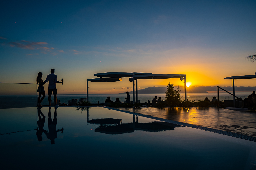Paar auf einer Terrasse bei Sonnenuntergang vor dem Meer auf Teneriffa.