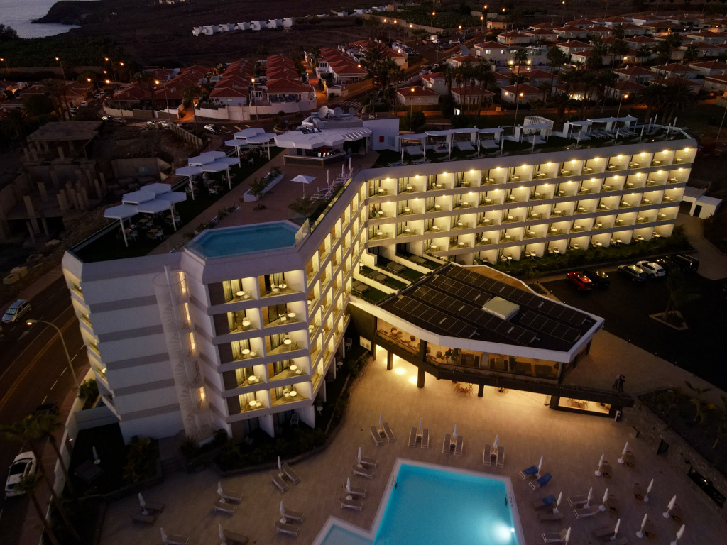 Beleuchtetes Gebäude mit Dachpool auf Teneriffa bei Sonnenuntergang.