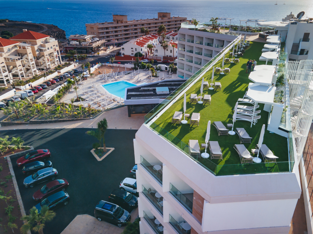 Terrasse mit Sonnenliegen und Sonnenschirmen in der Nähe des Pools, Teneriffa-Küste im Hintergrund.