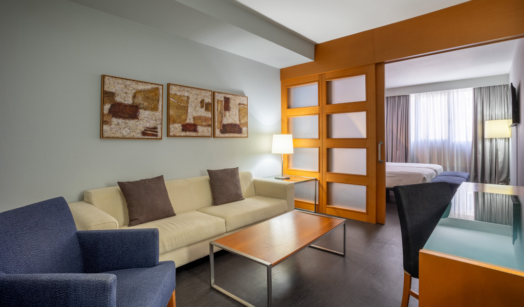 Hotelwohnzimmer auf Teneriffa mit Sofa, Tisch und Kunstwerken an der Wand.