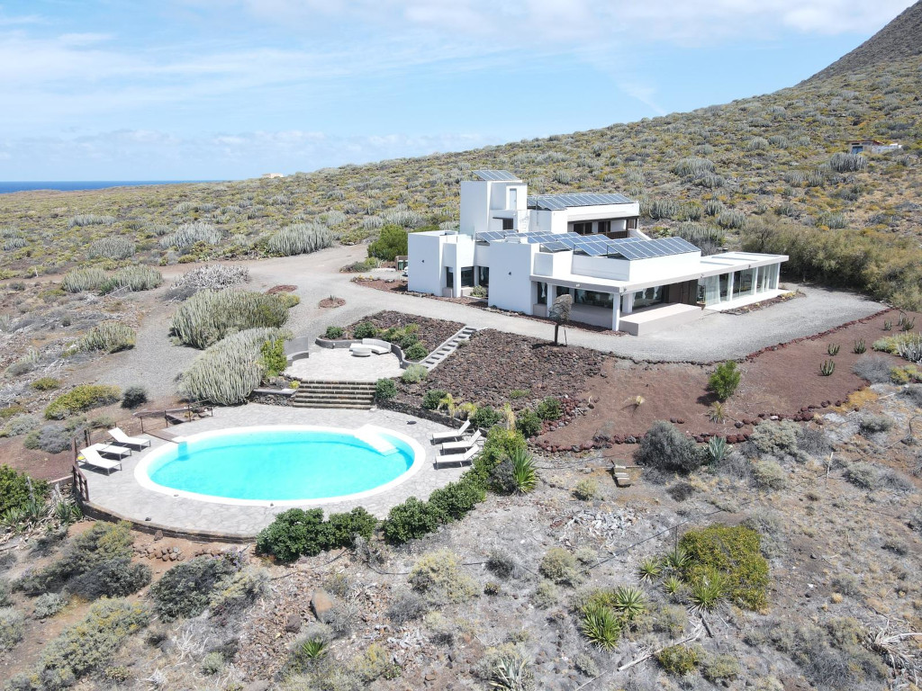 Weißes Haus mit Schwimmbad und Solarpanels in der trockenen Landschaft von Teneriffa.