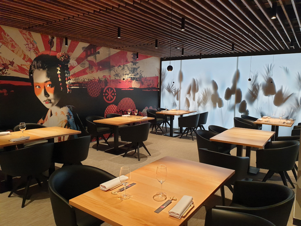 Restaurant mit Holztischen und einem Geisha-Wandbild an einer Wand auf Teneriffa.