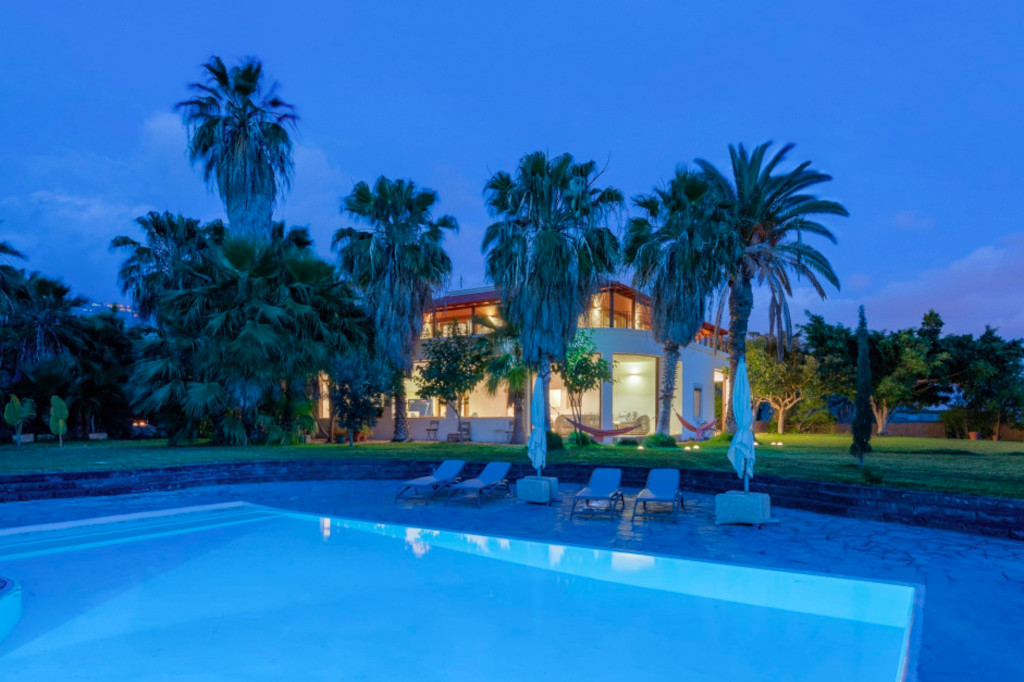 Haus mit Pool und Palmen bei Sonnenuntergang auf Teneriffa.