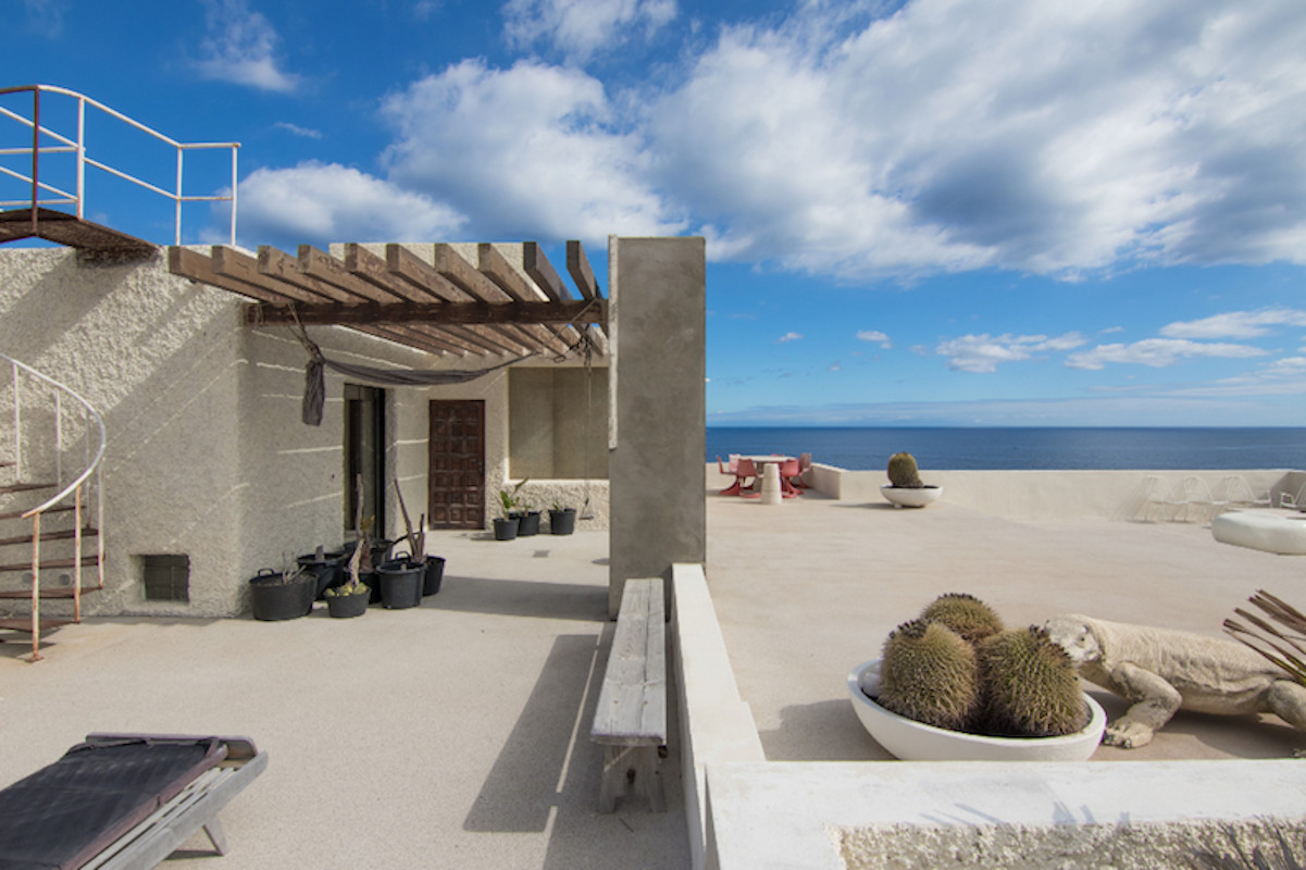 Terrasse mit Meeresblick auf Teneriffa, mit Stühlen, Kaktus- und Leguandekorationen.