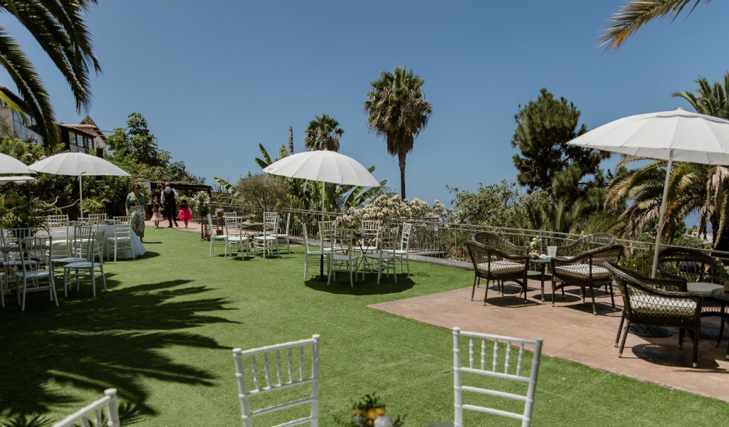 Garten mit Stühlen und Tischen unter Sonnenschirmen an einem Ort auf Teneriffa.