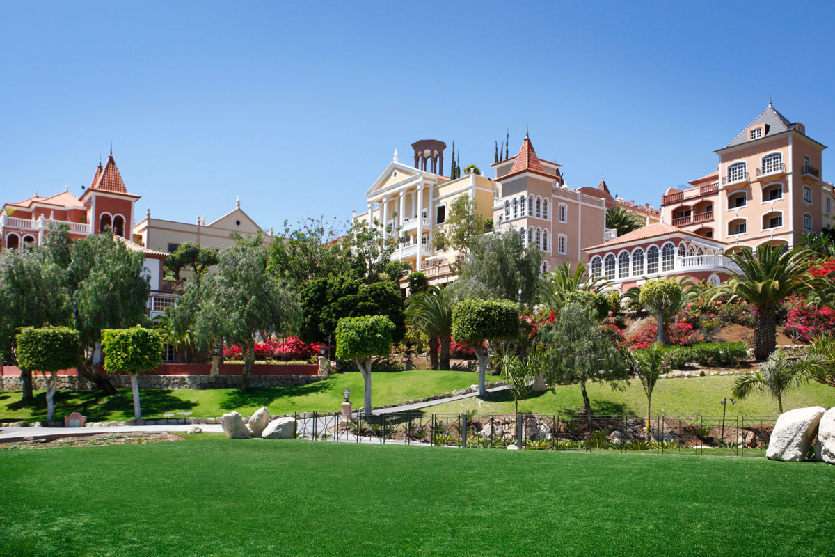 Bunte Gebäude, umgeben von Gärten und Palmen auf Teneriffa.