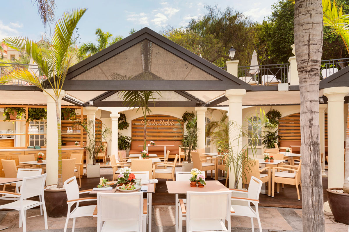 Terrasse des Café La Bahía auf Teneriffa, mit Tischen und Grünflächen rundherum.