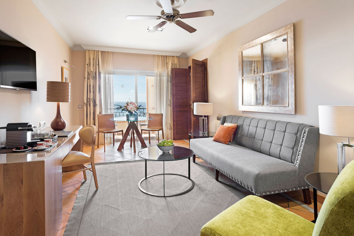Wohnzimmer mit grauem Sofa, Glastisch und Meeresblick in einem Hotel auf Teneriffa.