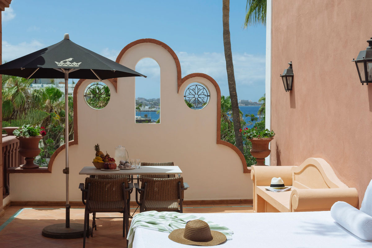 Terrasse auf Teneriffa mit Tisch, schwarzem Sonnenschirm und Meeresblick im Hintergrund.