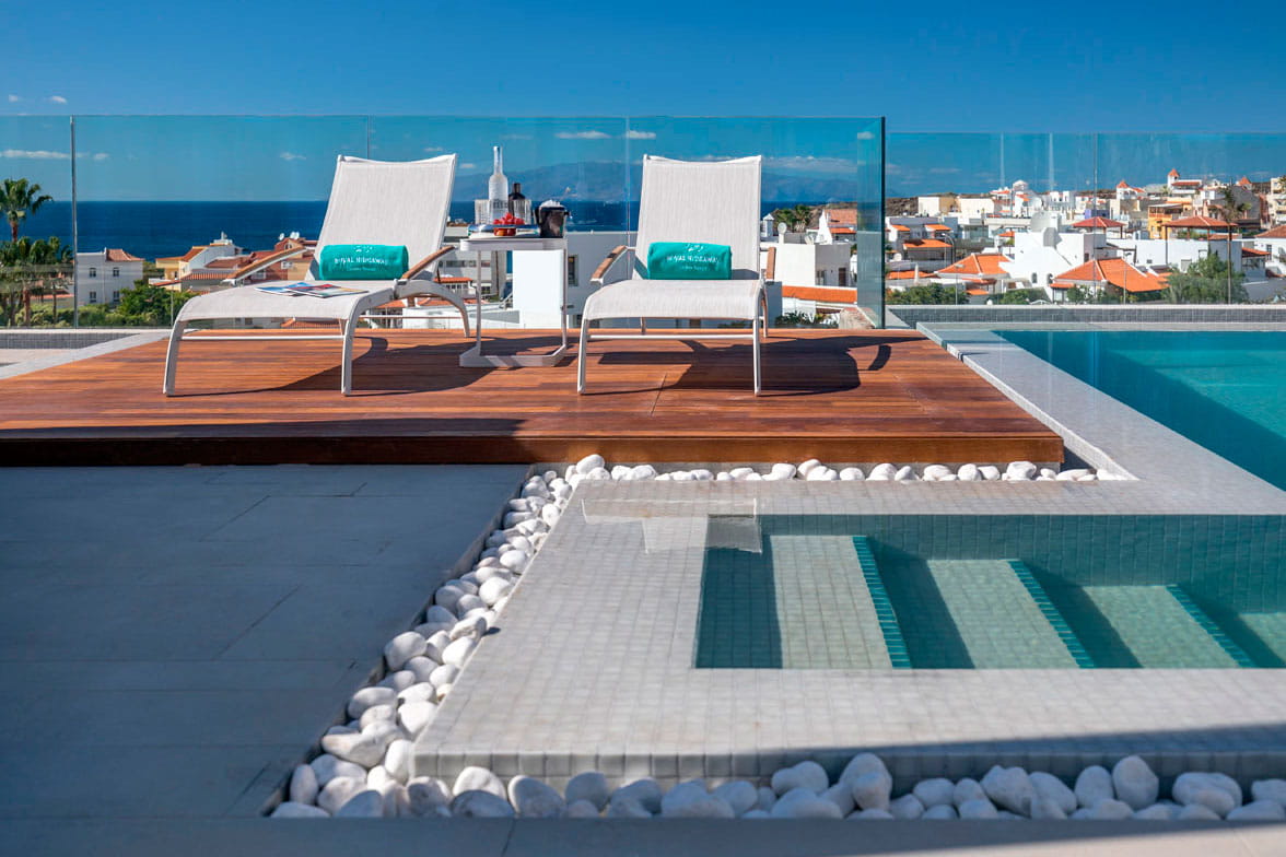 Sonnenliege an einem Pool mit Blick auf das Meer und die Stadt auf Teneriffa.