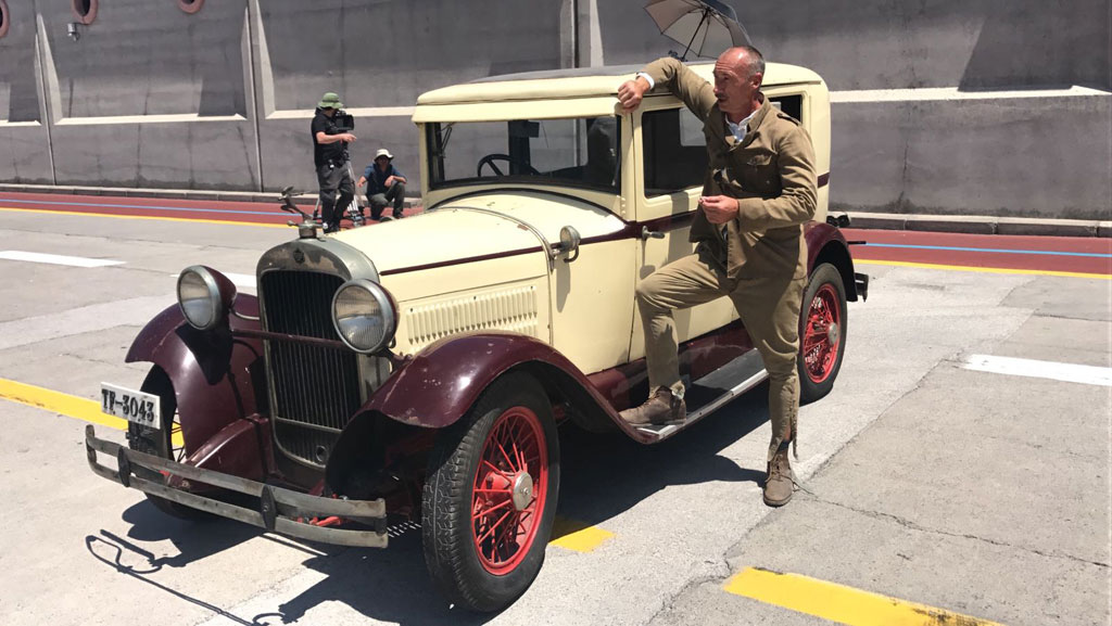 Mann, der sich an einen Oldtimer auf einer Straße in Teneriffa lehnt.