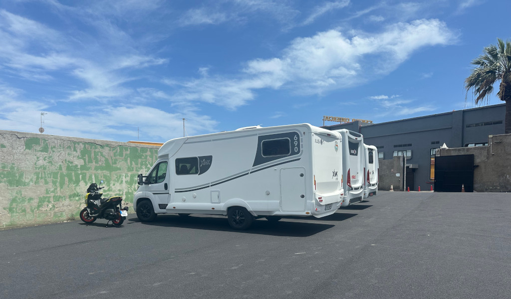 Wohnmobile und ein Motorrad stehen auf einem Parkplatz auf Teneriffa.
