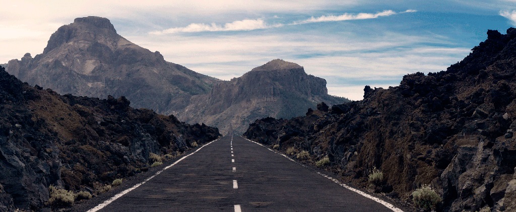 Gerade Straße, umgeben von vulkanischer Berglandschaft auf Teide, Teneriffa.
