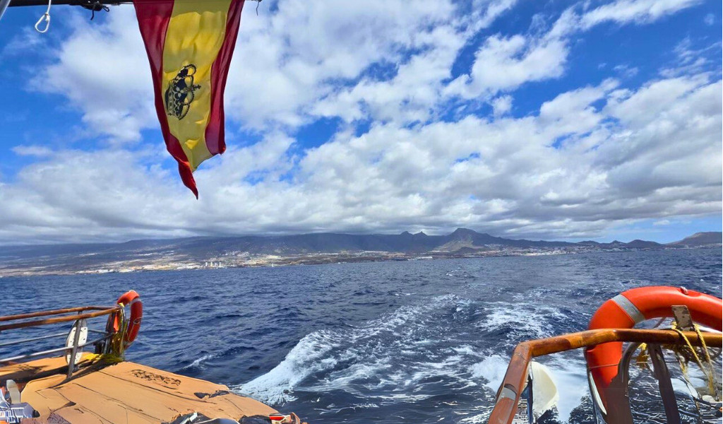 Bootsfahrt vor der Küste Teneriffas mit spanischer Flagge und Berglandschaft im Hintergrund.