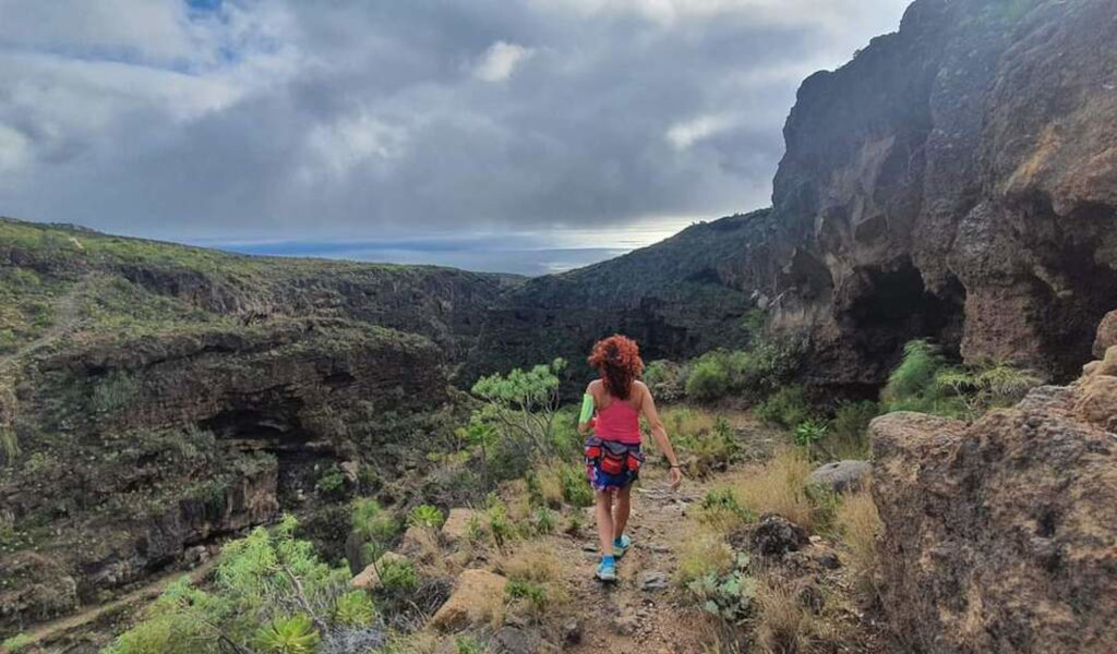 Person wandert im Barranco del Infierno auf Teneriffa mit bewölktem Himmel.