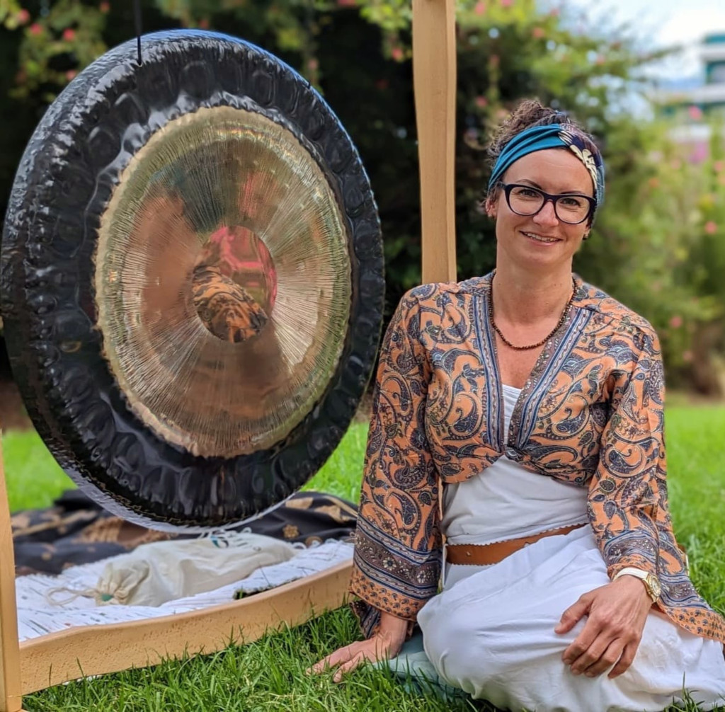 Frau sitzt im Garten von Teneriffa neben einem großen Gong.