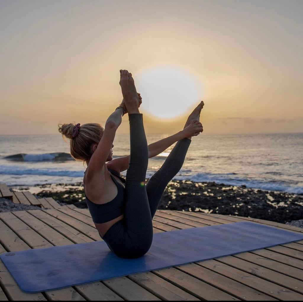 Person praktiziert Yoga bei Sonnenuntergang am Strand von Tenerife.