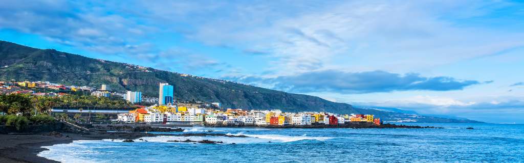 Bunte Häuser am Meer vor Bergen in Puerto de la Cruz, Teneriffa.