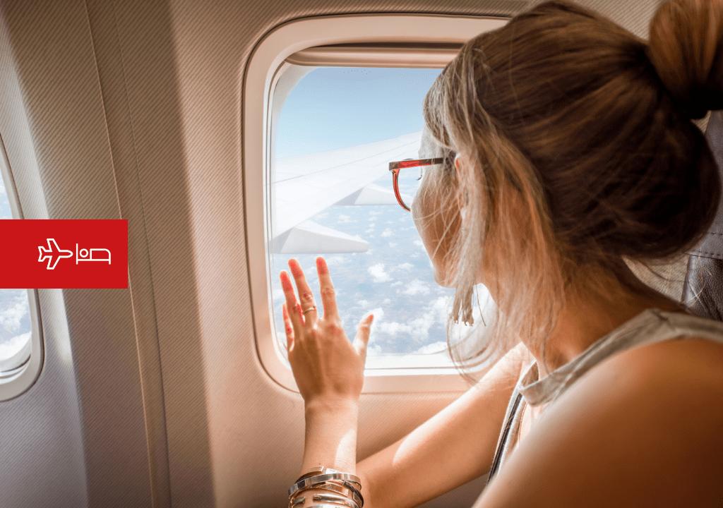Frau, die aus dem Flugzeugfenster auf dem Weg nach Teneriffa schaut.