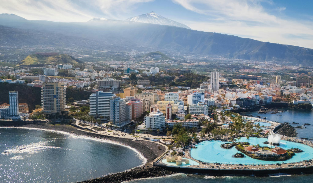 Luftaufnahme von Puerto de la Cruz, Teneriffa, mit Küstenlinie und hohen Gebäuden.