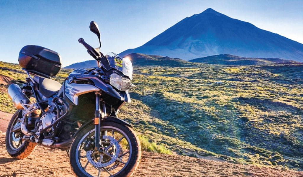 Motorrad vor dem Teide auf Teneriffa unter blauem Himmel geparkt.