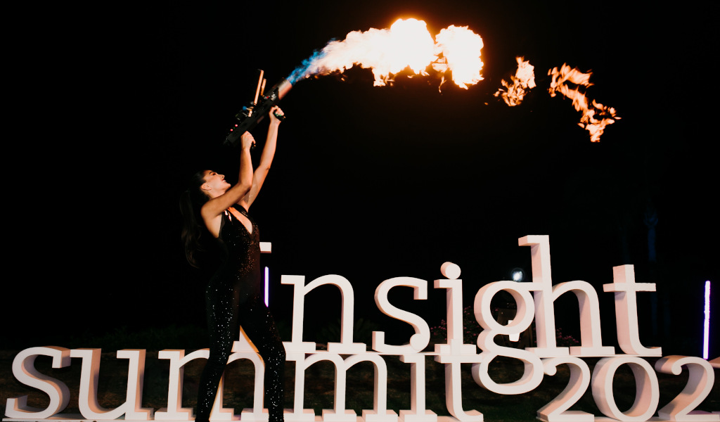 Flammenwerfer-Person neben Insight Summit 2021 Buchstaben bei einer Nachtveranstaltung auf Teneriffa.