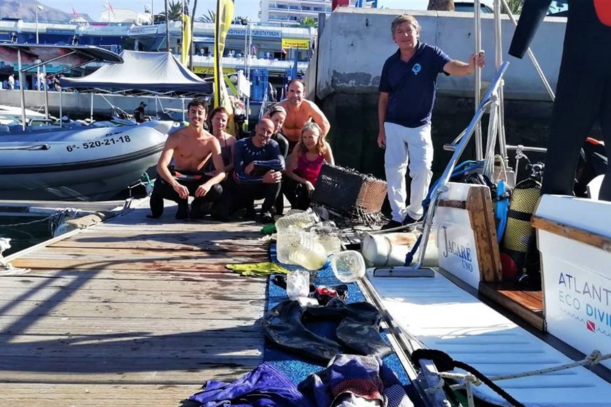 Menschen am Steg mit Tauchausrüstung und Müll, die auf Teneriffa gesammelt wurden.