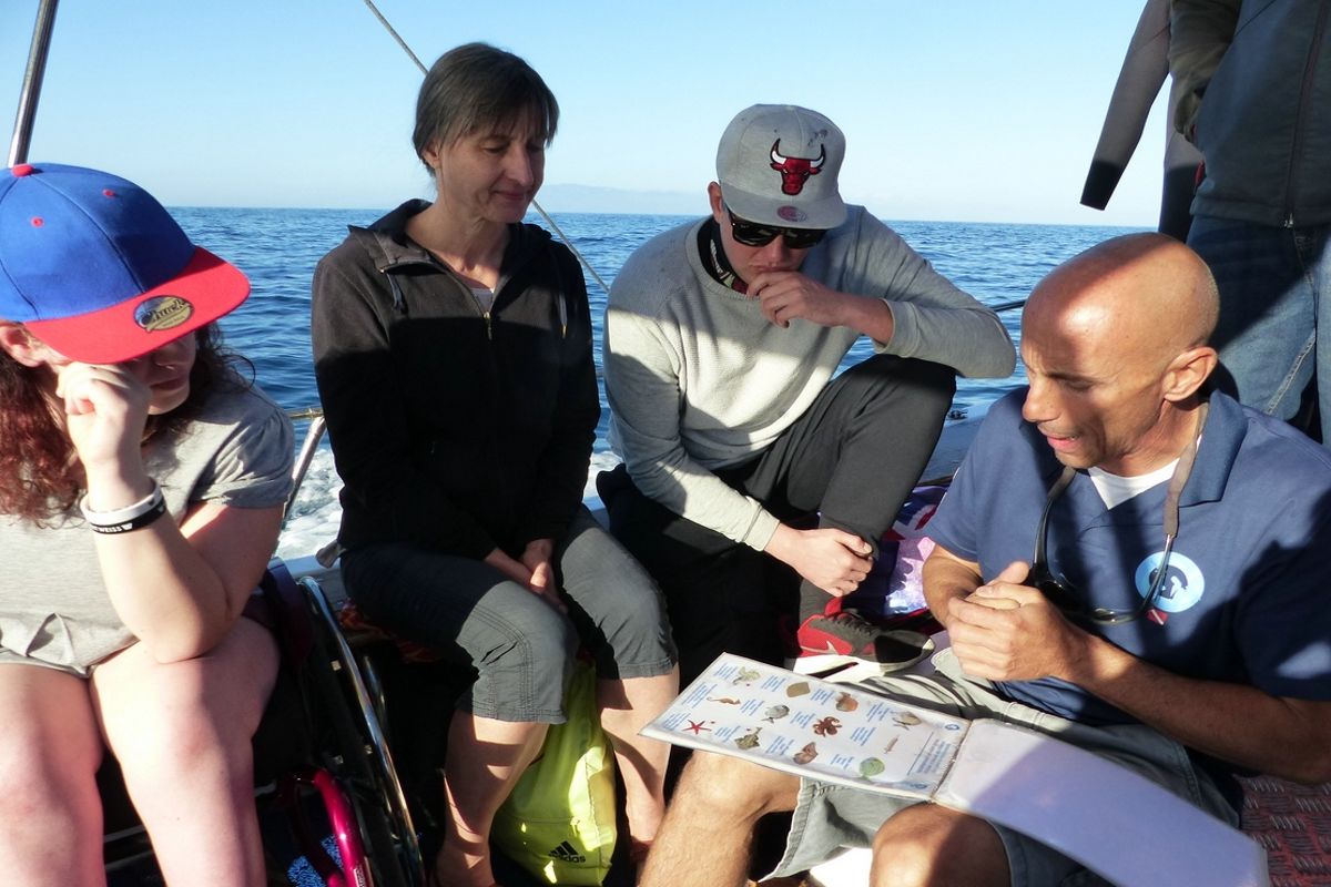 Menschen auf einem Boot auf Teneriffa schauen sich eine Liste mit Bildern und Text an, während sie segelen.