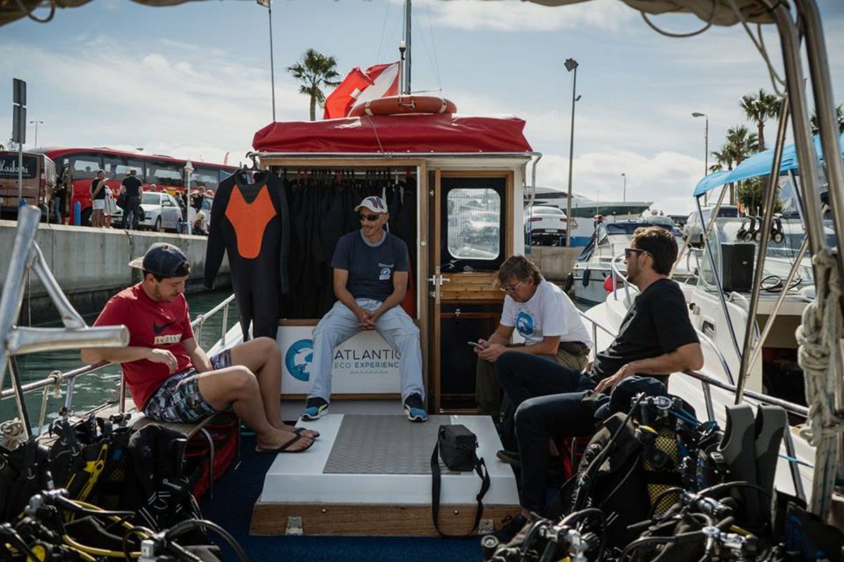 Menschen, die auf einem Tauchboot in Puerto Colón, Teneriffa, sitzen und Neoprenanzüge tragen.