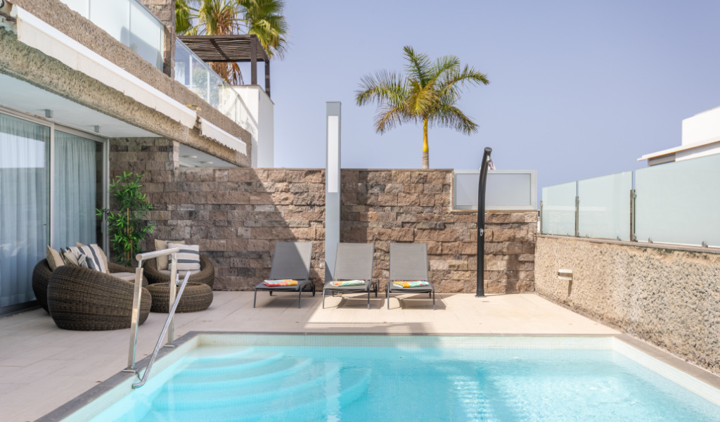 Freies Schwimmbad mit Stühlen und Palme in einem Hotel auf Teneriffa.
