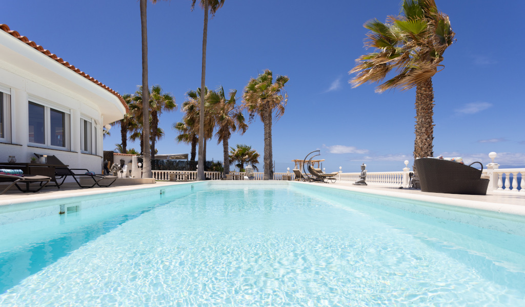 Freies Schwimmbad mit Palmen auf Teneriffa bei klarem Himmel.