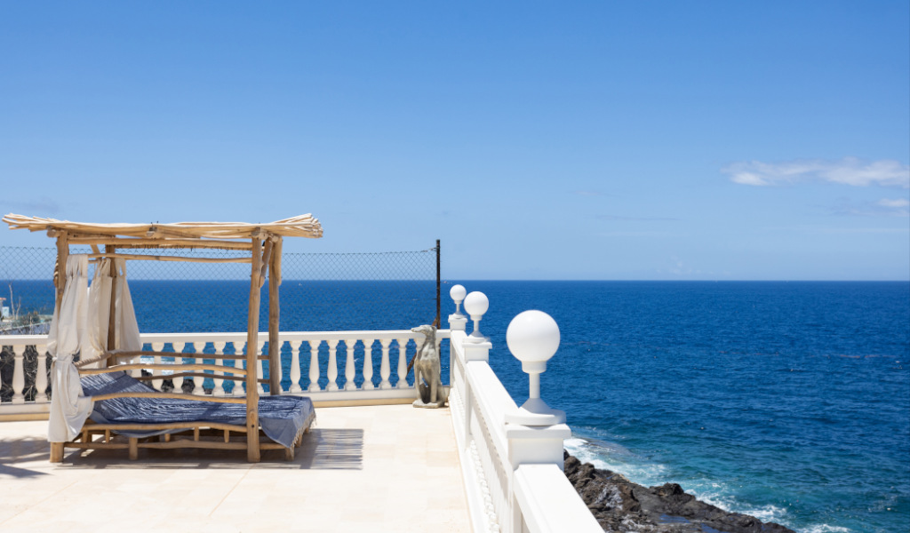 Holzliegestuhl mit Blick auf das Meer auf Teneriffa bei klarem Himmel.