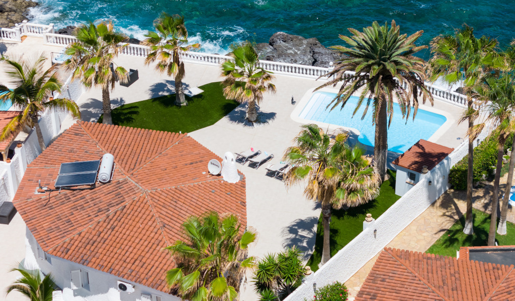 Luftaufnahme der Terrasse mit Pool, Palmen und Meer auf Teneriffa.