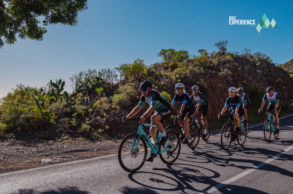 Radfahrer auf einer bergigen Strecke auf Teneriffa, mit dem Bike Experience-Logo.