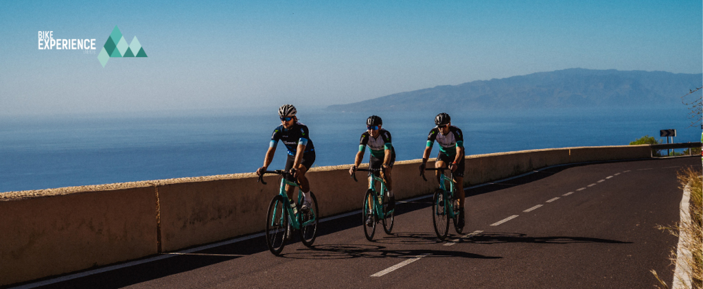 Radfahrer auf der Straße mit Meer und Blick auf Teneriffa. Text: Fahrraderfahrung.