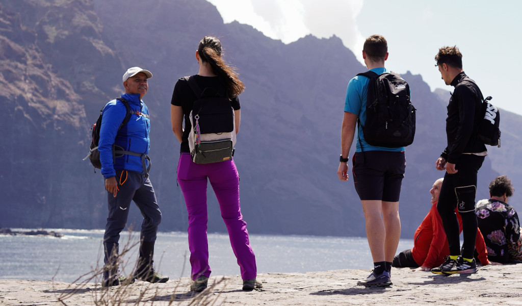 Eine Gruppe von Menschen mit Rucksäcken vor Klippen auf Teneriffa.
