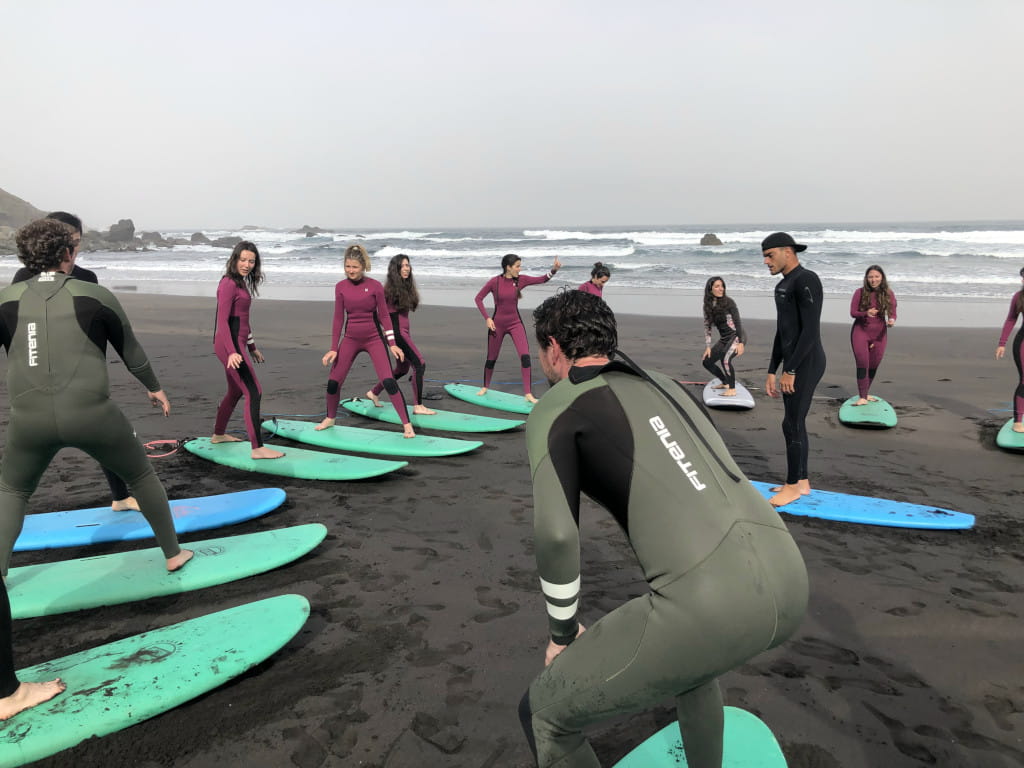 Eine Gruppe von Menschen, die am Strand von Teneriffa surfen lernen.