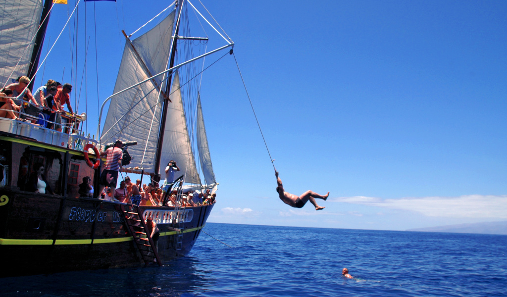 Die Person springt vom Touristenboot an der Küste Teneriffas aufs Meer.