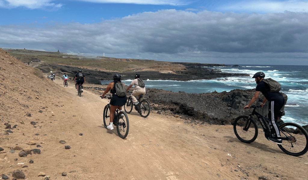 Radfahrer, die auf einem Küstenweg auf Teneriffa am Meer und bei bewölktem Himmel fahren.