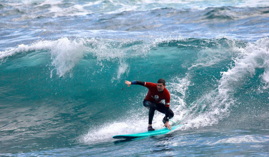 Surfer, der auf einer Welle am Strand auf Teneriffa reitet.