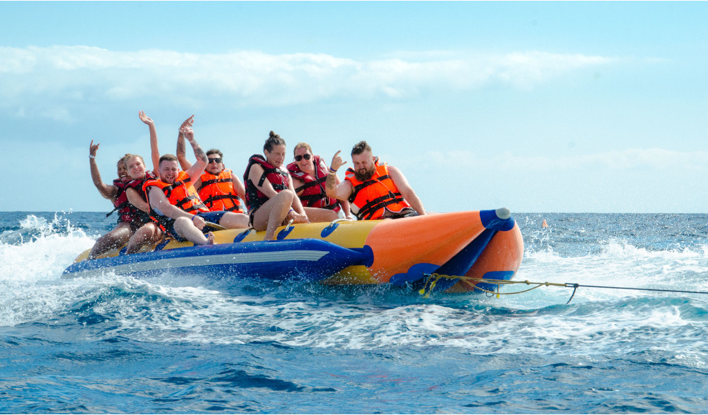 Menschen auf einem aufblasbaren Bananenboot über dem Meer bei einer Wasseraktivität auf Teneriffa.